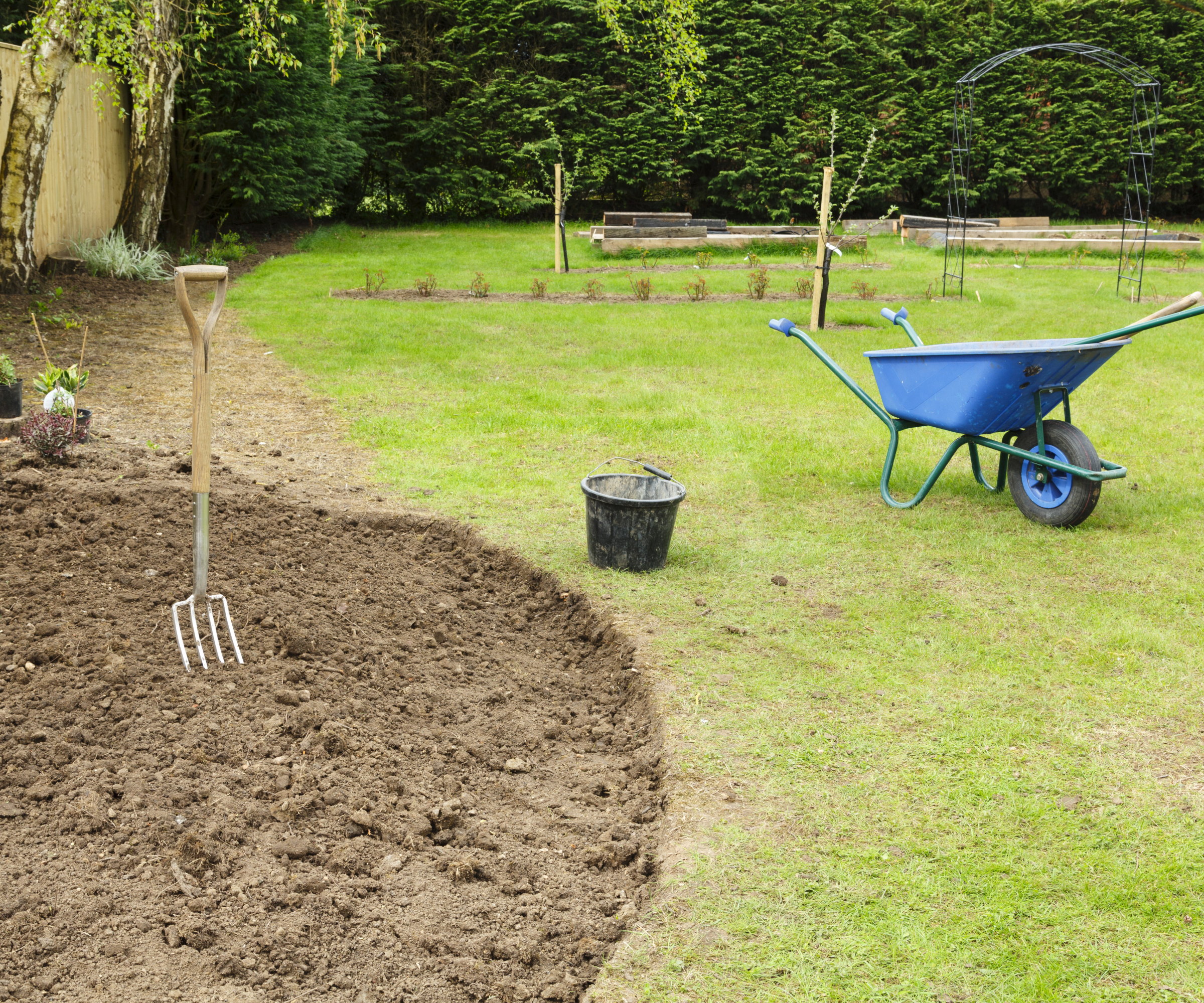 Preparing a flower bed with soil and a wheelbarrow full of garden tools