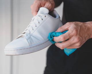 Wiping white sneaker with blue microfiber cloth