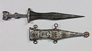 The restored dagger and sheath. Both are decorated with red glass.