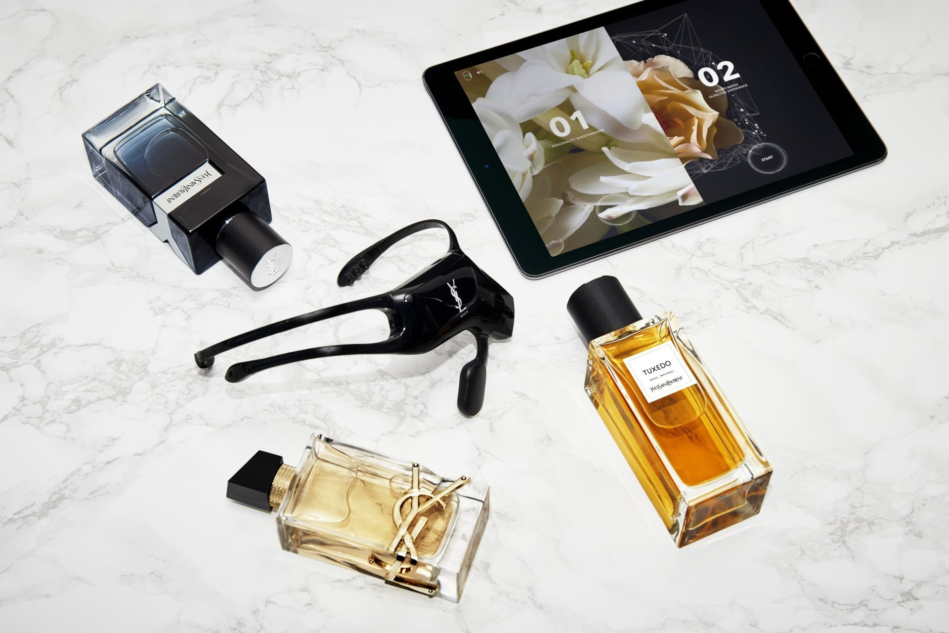 bottles of perfume, a headset and a tablet screen