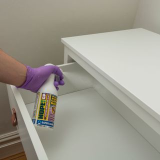 White empty chest of drawers being sprayed with moth spray