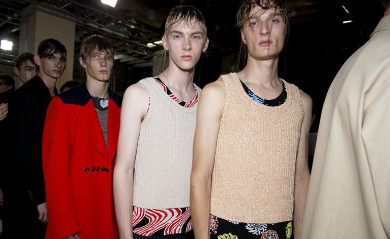 A queue of models in a dark room looking at the camera