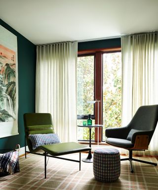 room with green walls, large window with neutral drapes and mid-century modern chairs
