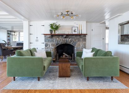 Living room with green sofas facing, fireplace and wood floor