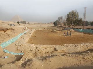 An image of the OK (Old Kingdom) Corral with the Giza pyramids in the distance. Researchers note that it was large enough to hold 55 cattle with feeding pens. There may also have been areas for slaughter.