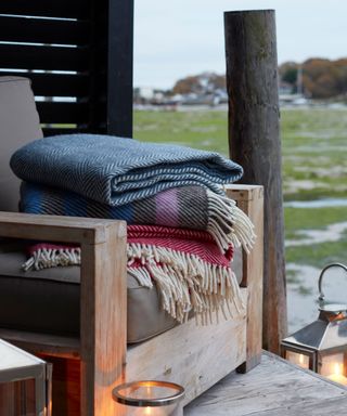 folded blankets on a chair in outdoor space with candles