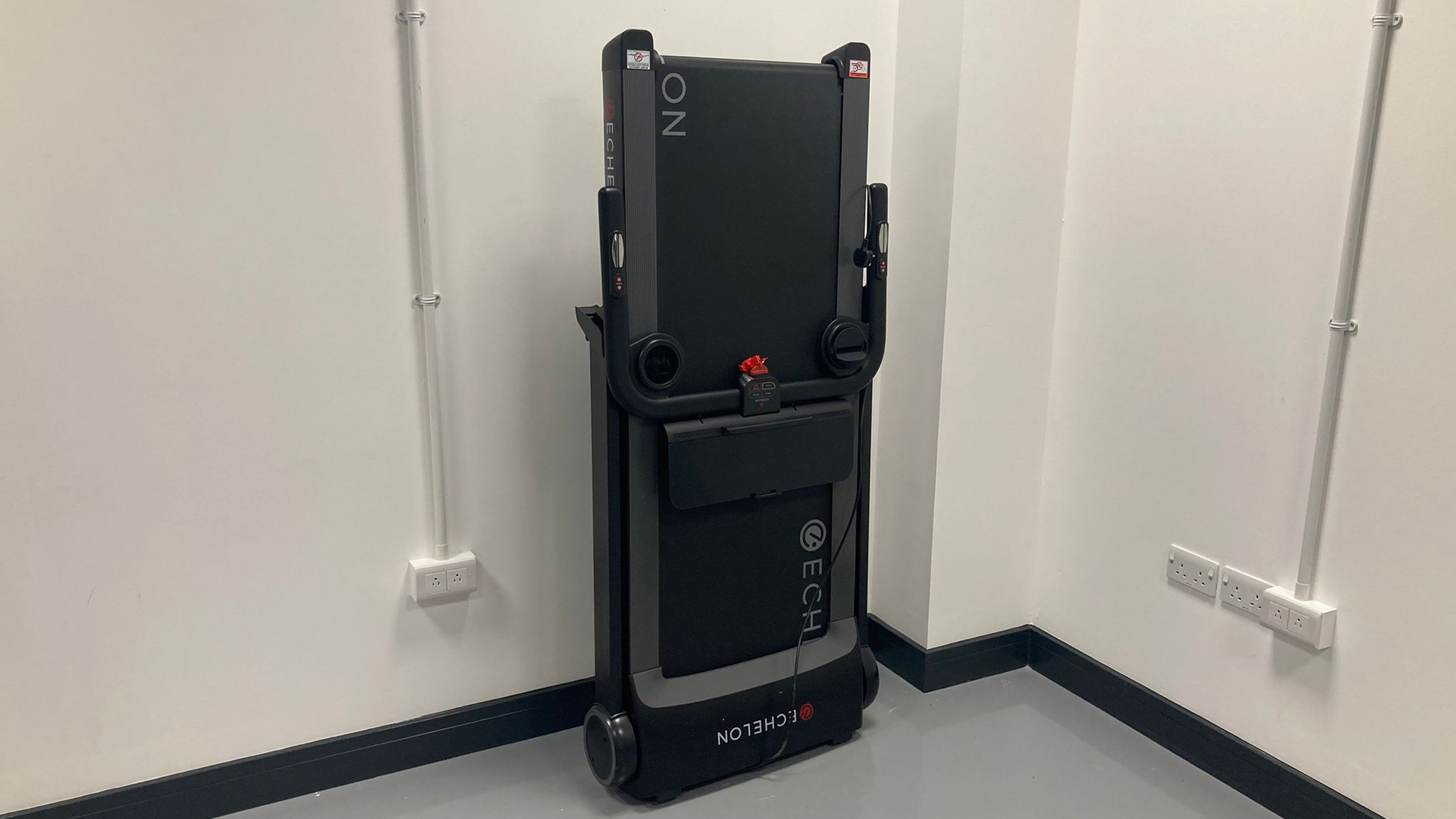 The Echelon Stride treadmill folded up and leant against a wall