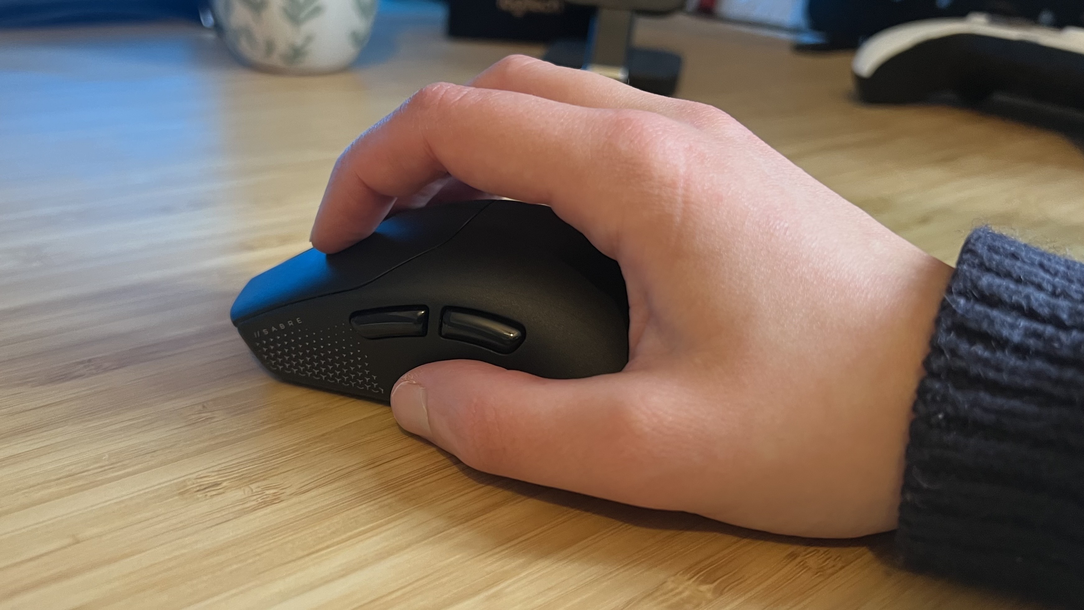Corsair Sabre Pro V2 Ultralight being used by a reviewer on a wooden desk