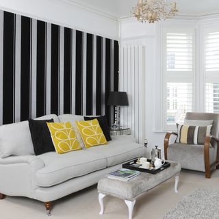 Black and silver striped wallpaper feature wall behind sofa in living room