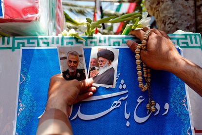 A mourner carries photos during the funeral of a victim of the Tehran attacks on June 7.