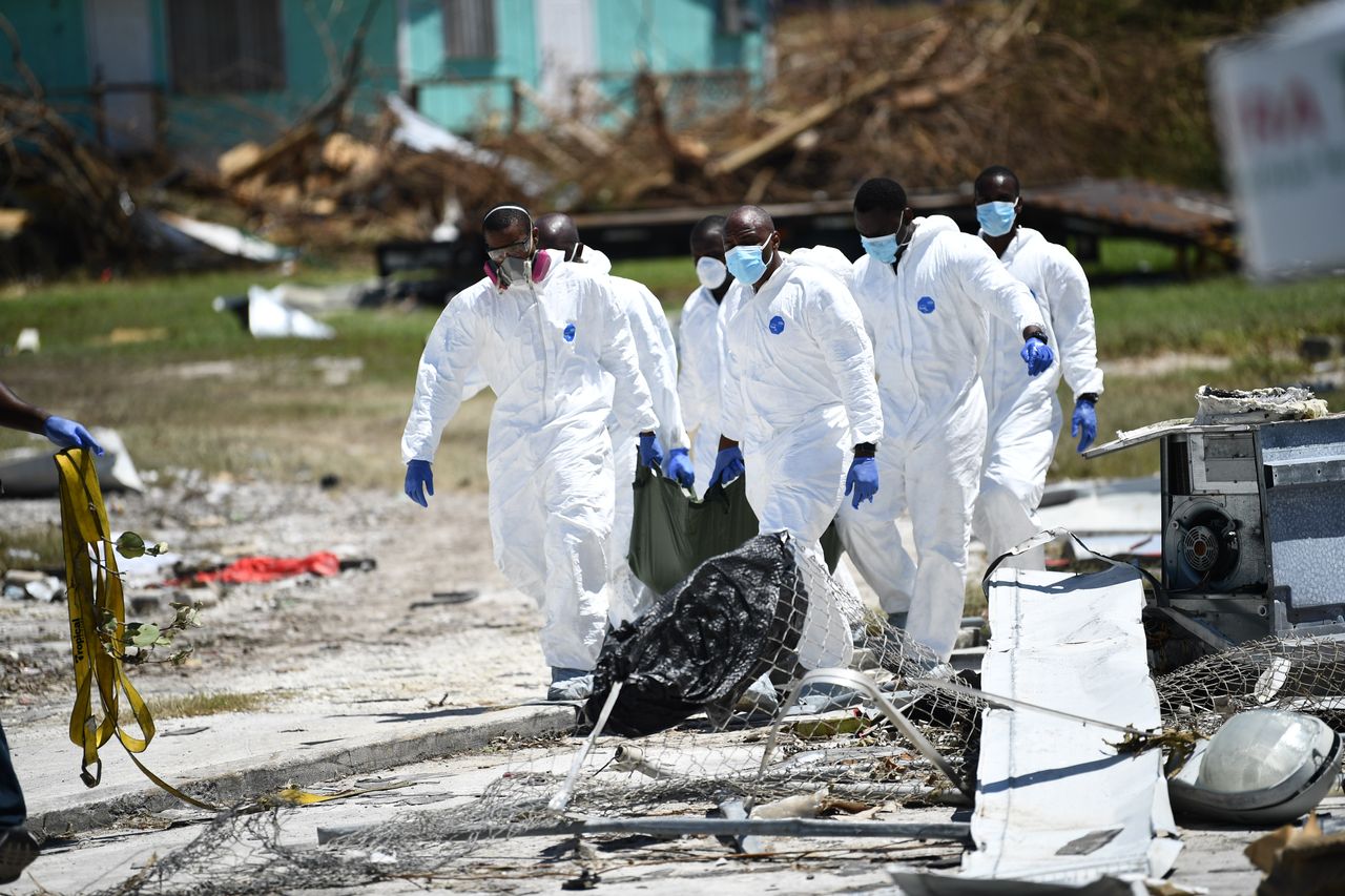 White-clad rescue workers carry a body in a black bag