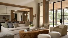 Living room with large glass doors, stone coffee table, neutral sofa and armchairs and round boucle ottomans