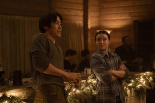 young mazino and bella ramsey in the last of us season 2 talking inside a cabin