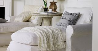 white living room with white chaises with tactile cushions and throws to suggest how to create a stress-free home
