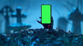 A smartphone held in a zombie had, emerging from a spooky crypt