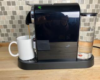 Making a lungo (long coffee) using the Nespresso Citiz espresso maker. Coffee is being dispensed into a white ceramic mug