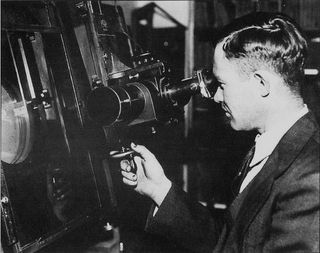 Clyde Tombaugh, discoverer of Pluto, peers into an instrument.