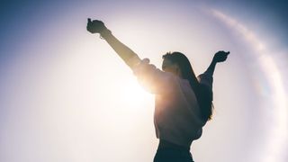 How to build resilience in yourself and others - a woman raising her hands in the air