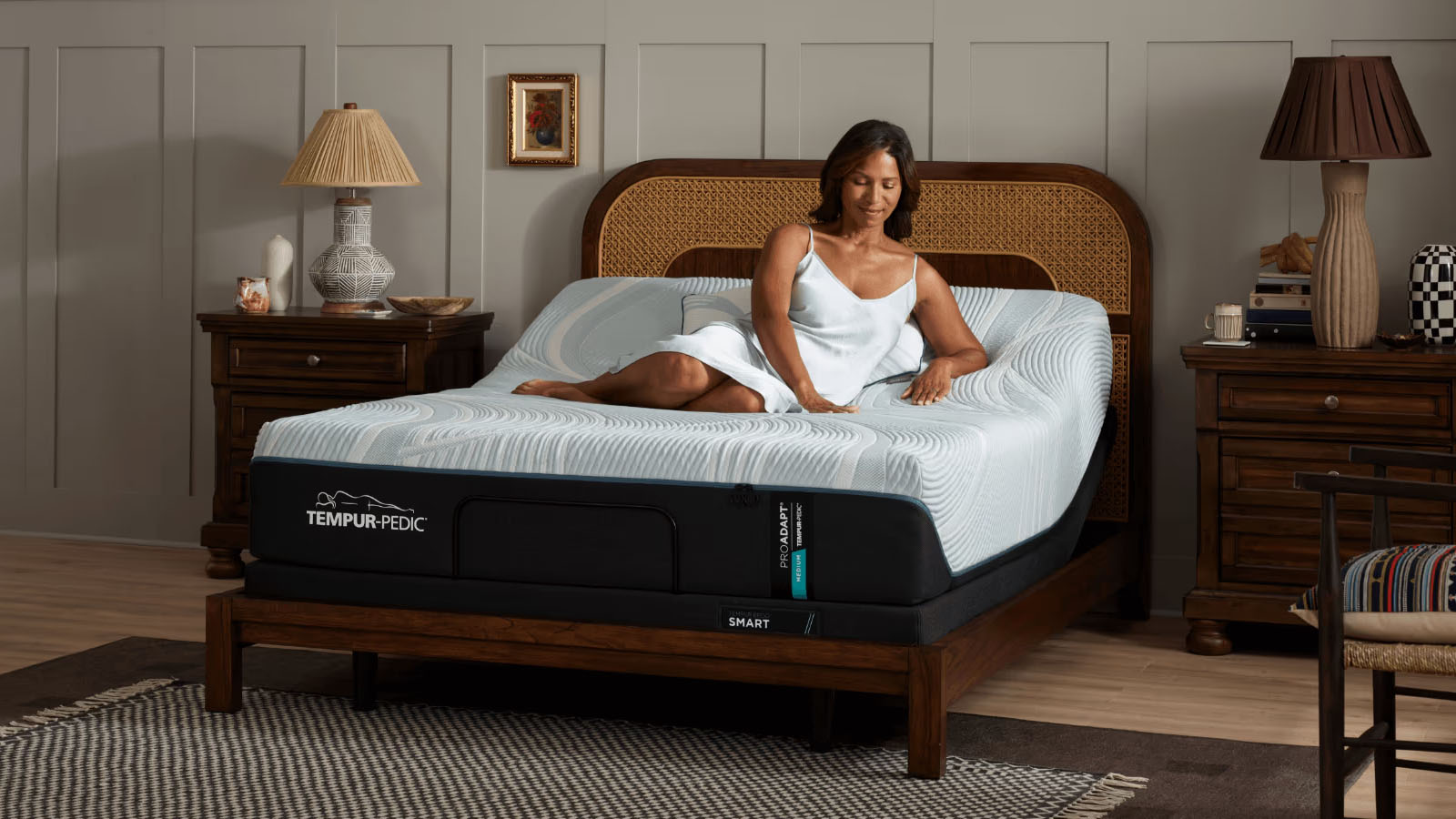 The Tempur-Pedic Tempur-ProAdapt mattress in a bedroom, a woman is sitting on top of the bed