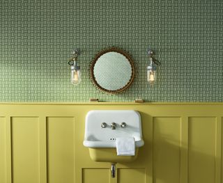 Green and yellow bathroom with circular mirror and industrial lighting