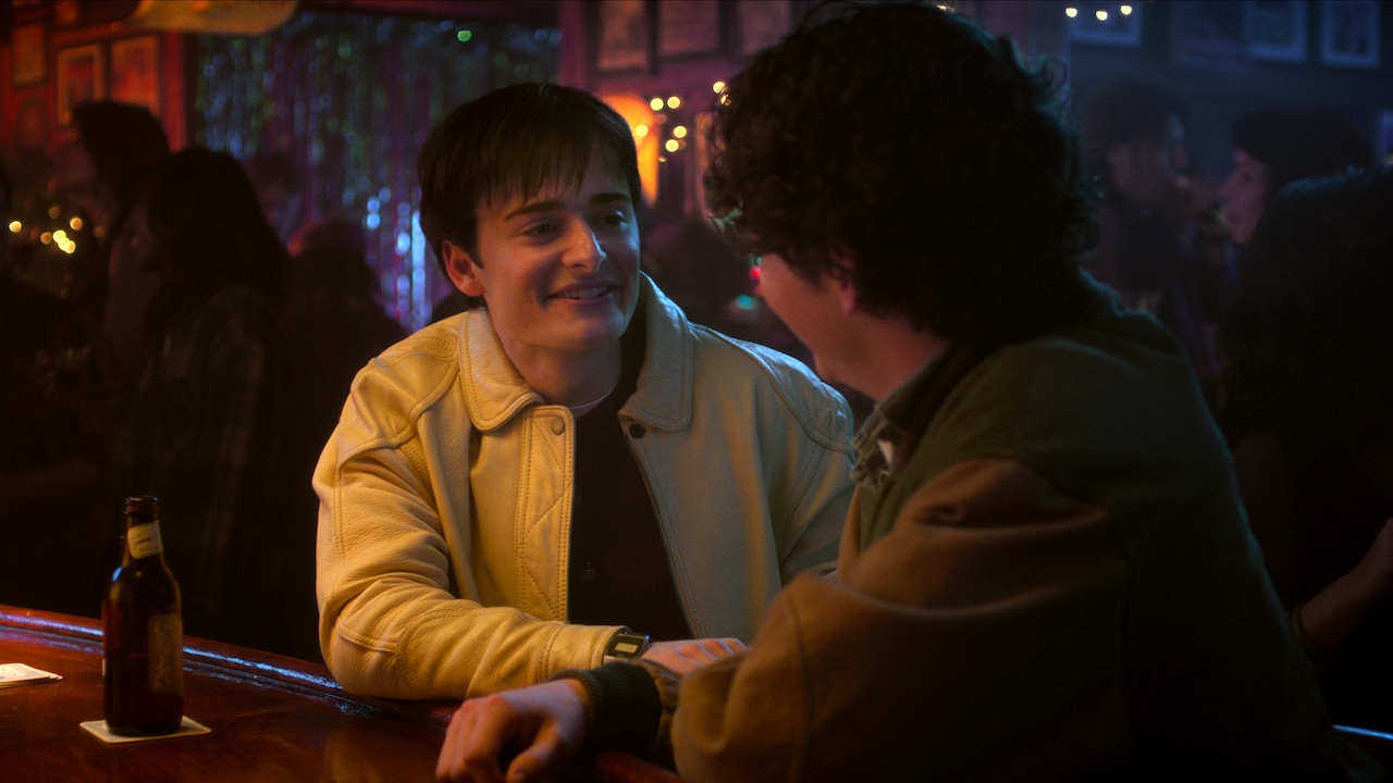 Noah Schnapp as Will Byers talking to a guy at a bar in Stranger Things series finale