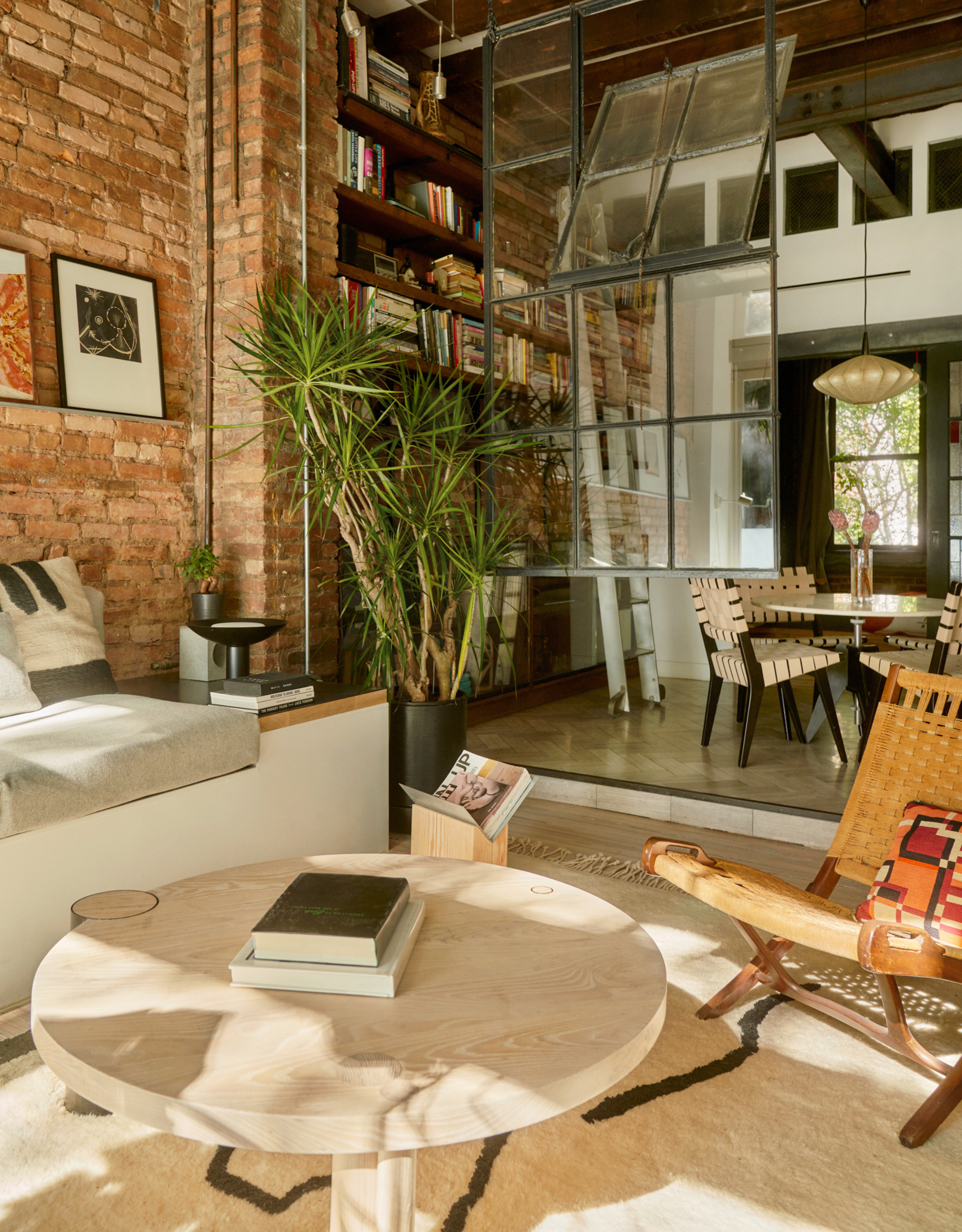 A living room with a round coffee table a flat rug, a woven chair, and a potted plant