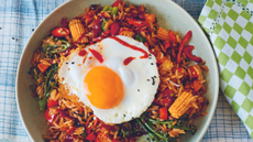 A photo of well-seasoned fried rice and vegetables topped with a fried egg