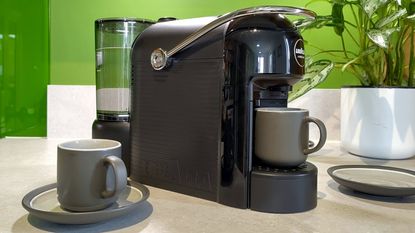 Lavazza Jolie Evo coffee maker on kitchen counter with espresso cups and saucers