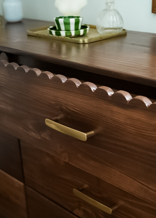 Small corner of wooden dresser at an angle with drawer open.