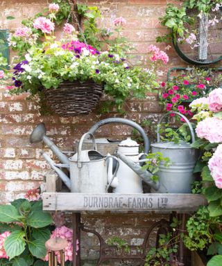 potting table in a courtyard garden with watering cans and hanging baskets