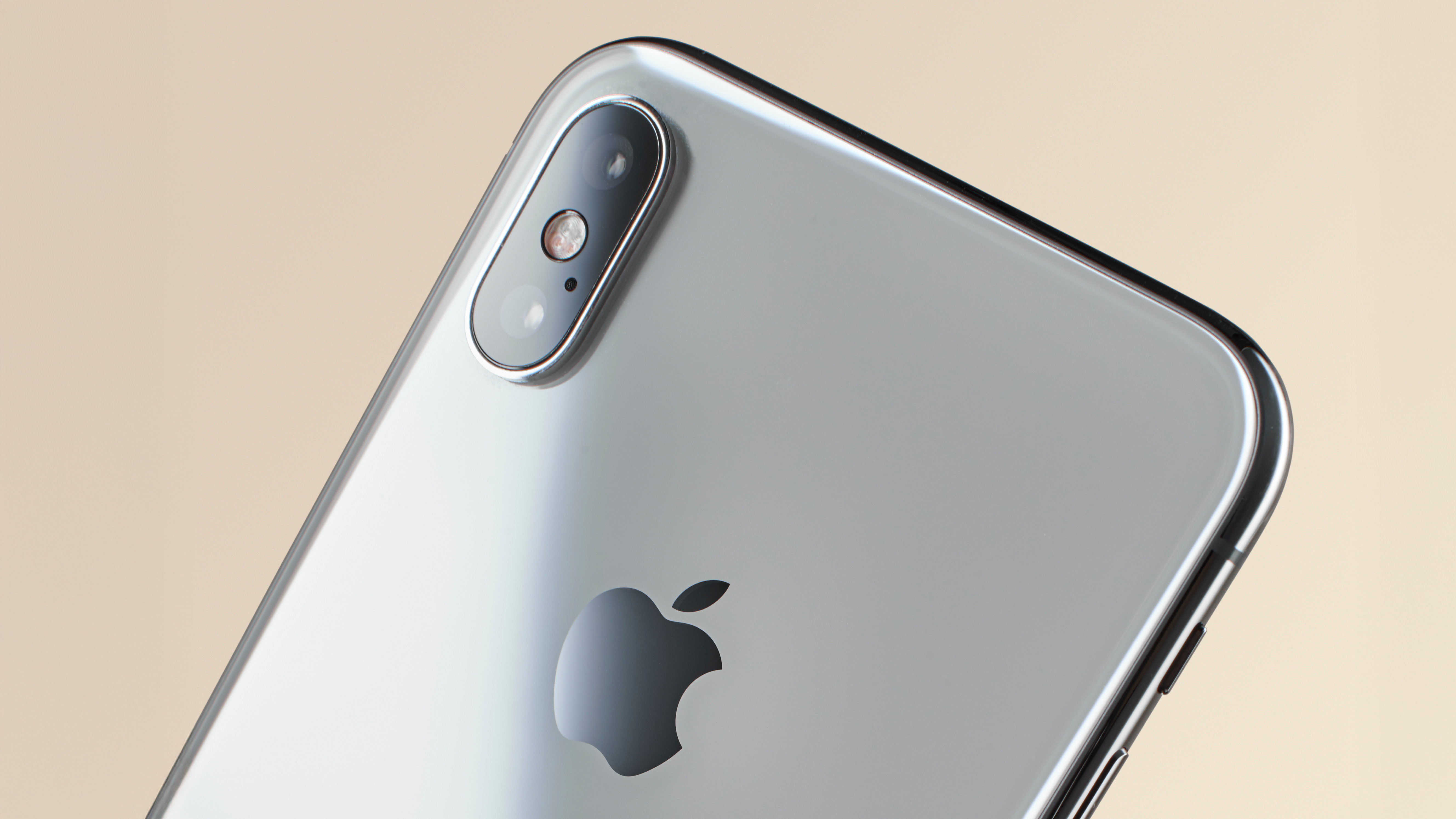 Silver iPhone X in front of a beige background