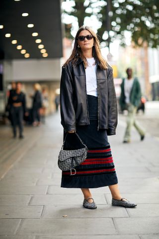 woman wearing jacket, white t-shirt, skirt, dior bag, and mary jane shoes