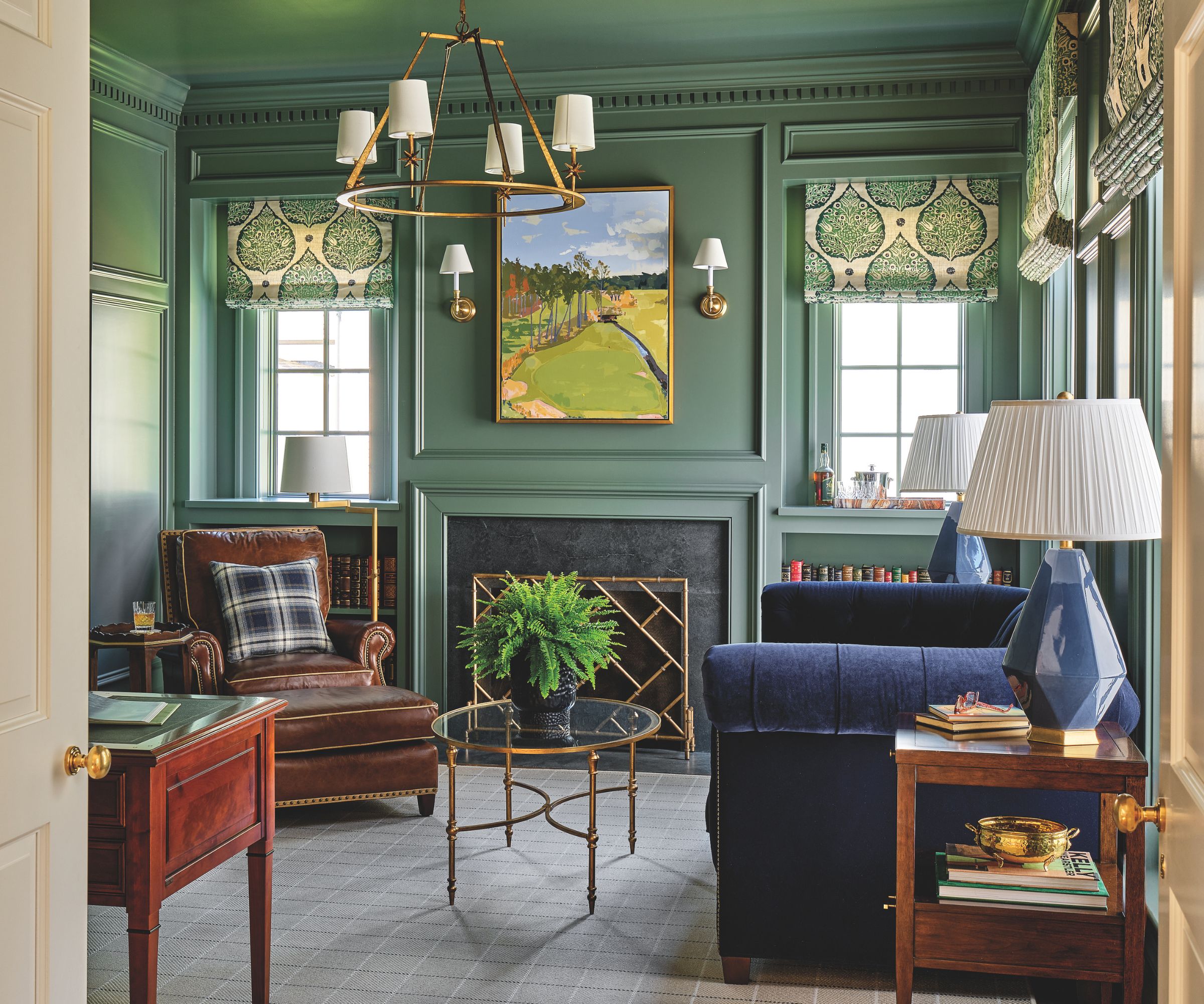 Heritage sitting room with green walls, blue velvet sofa, leather armchair and tartan carpet with gold candelabra chandelier