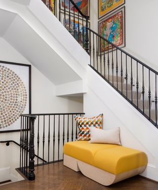 stairway with cream walls and yellow contemporary bench and bright Hermes scarves in frames