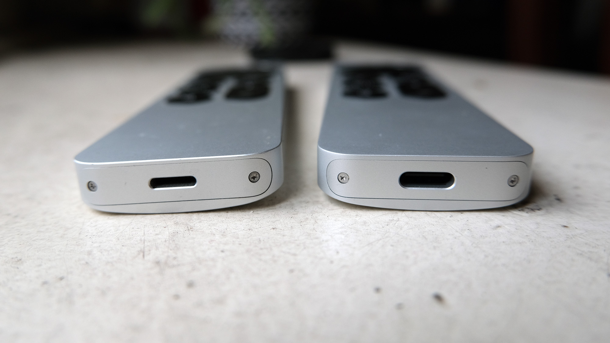 The Apple TV 4K remotes, showing (L, R) the Lightning port on the 2021 model and the USB-C port on the 2022 model.