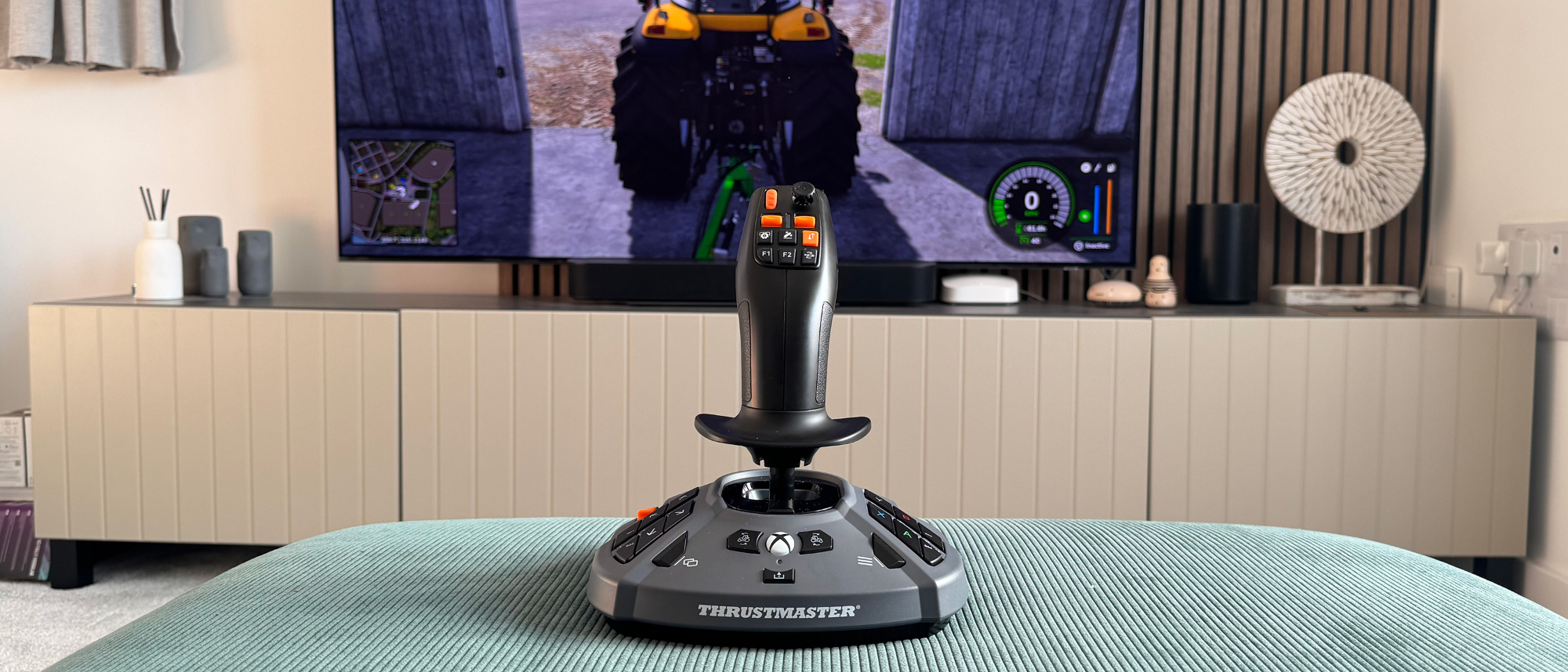 The Thrustmaster SimTask Farmstick X in front of a gaming TV