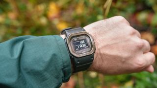 G-Shock smartwatch on wrist with out of focus foliage in background.