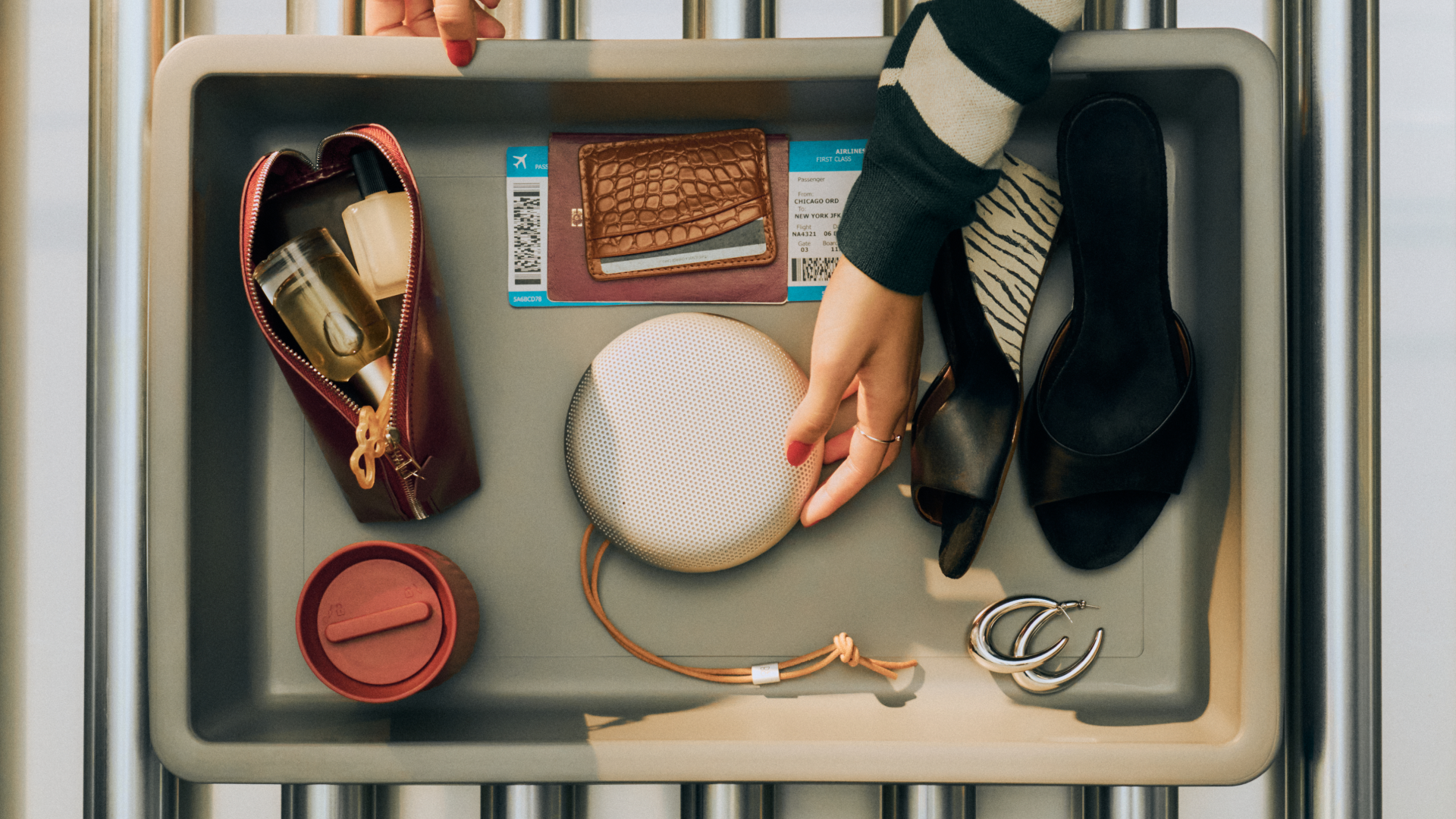 The Bang & Olufsen A1 3rd Gen on an airport security tray, along with other travel items
