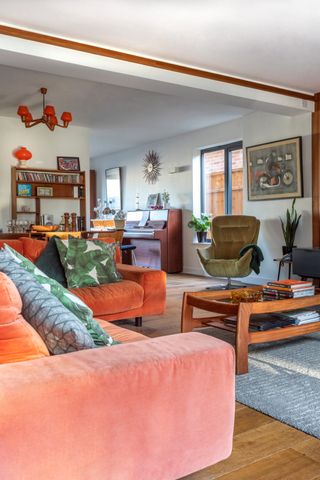 A living room with orange sofa and olive green velvet accent chair