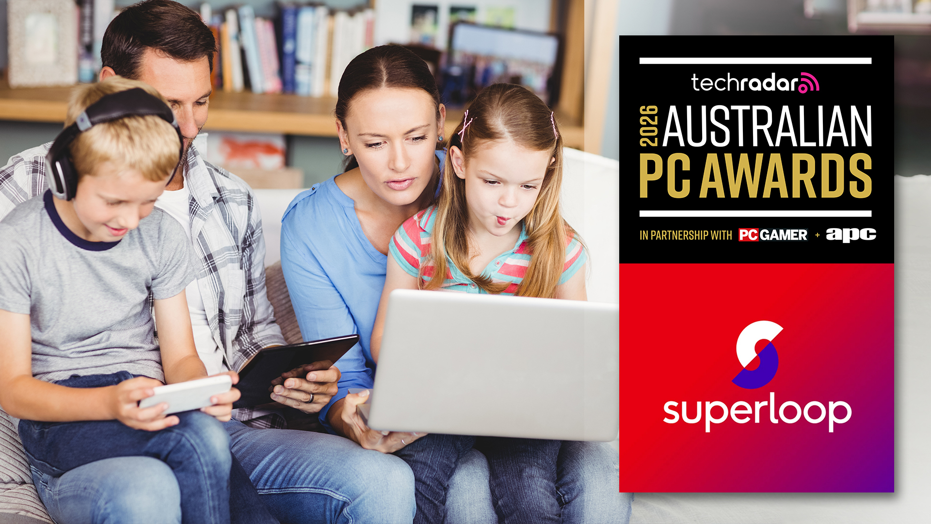 Family of 4 sitting on a sofa using connected devices. 