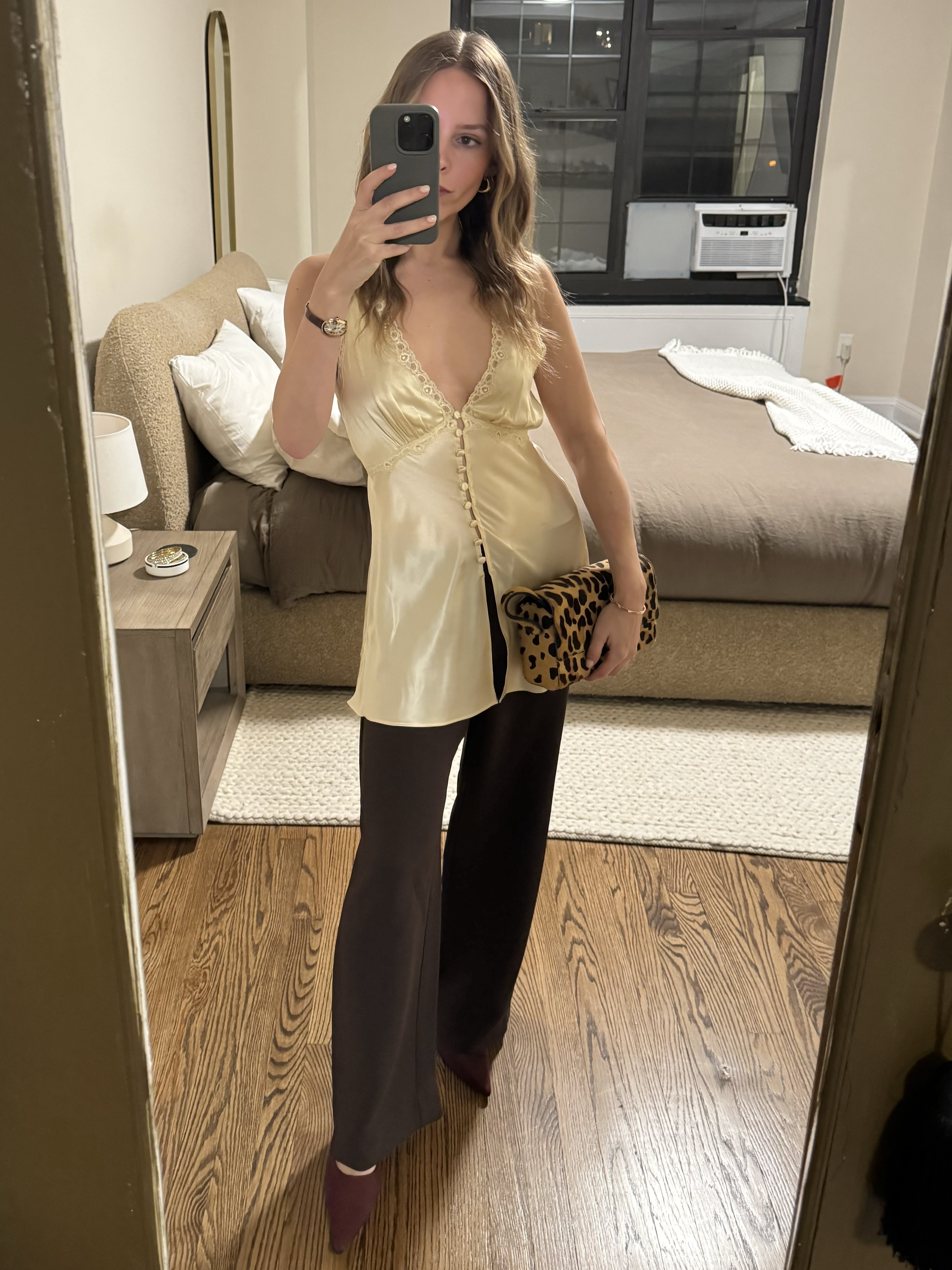 Nikki wears a off white silk top, leopard bag, brown pants, and burgundy heels.