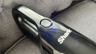 The Shark UltraCyclone Pet Pro Plus handheld vacuum on switch, with a light indicating that the vacuum is powered on