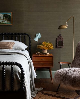 A bedroom with layered lighting of gold floor lamp and grey wall light
