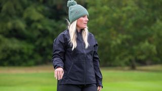 A golfer wears the Puma Women's DRYLBL Waterproof Rain Jacket