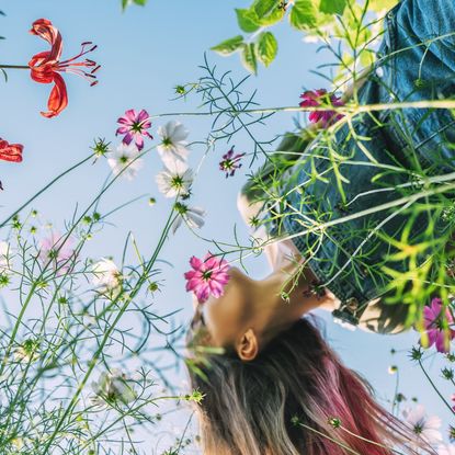 A woman holding her head up in a bed of flowers