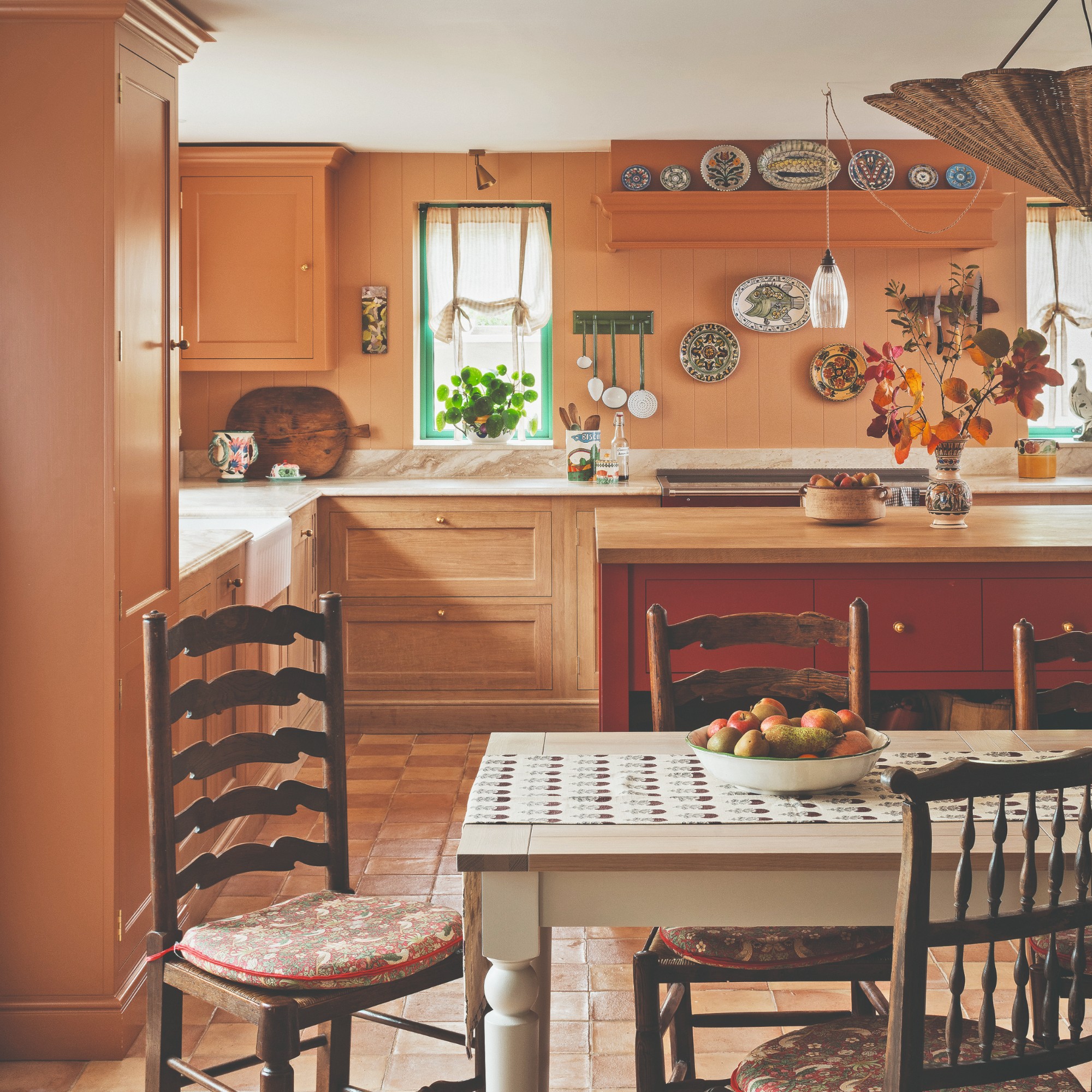 A kitchen painted in an earthy shade of orange with a red kitchen island