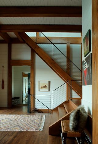 A split-level stairway with shiplap walls and Cyprus beams