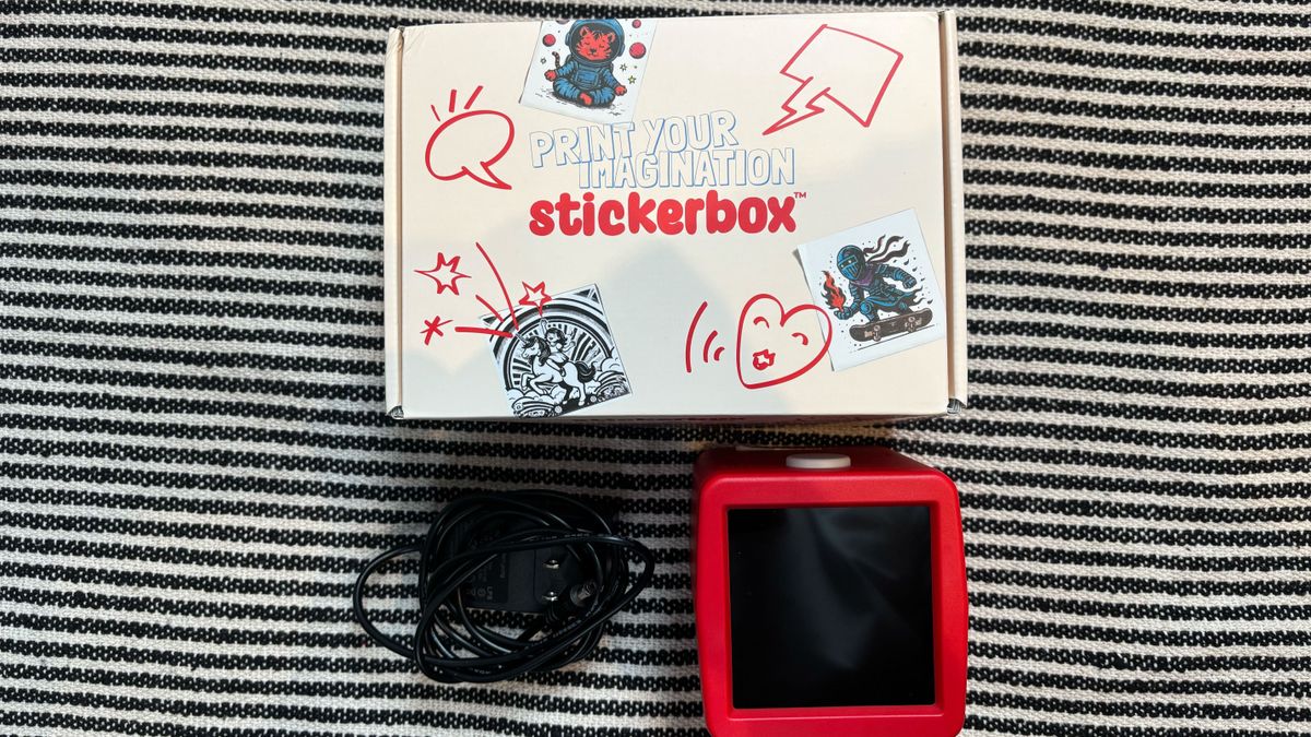 The Stickerbox device out of its packaging next to its plug-in cable