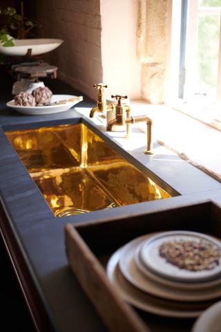 A polished brass sink and gold faucet