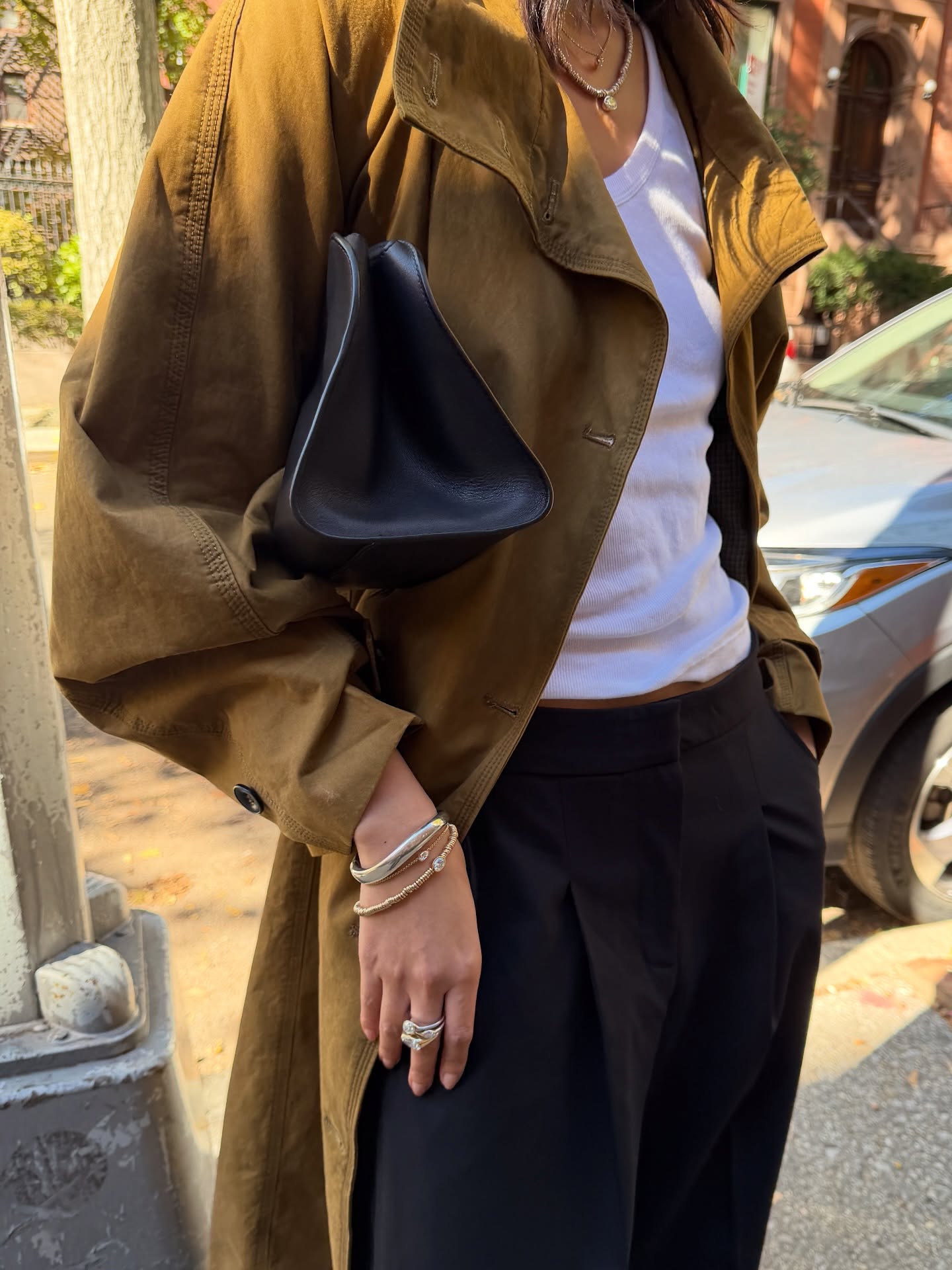 Mini Nguyen wears a trench coat, white tank top and black tailored trousers.